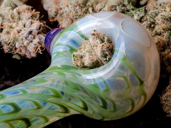 A close up of a glass smoking pipe, with cannabis