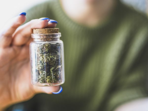 Unrecognisable woman holding a jar full of marijuana.